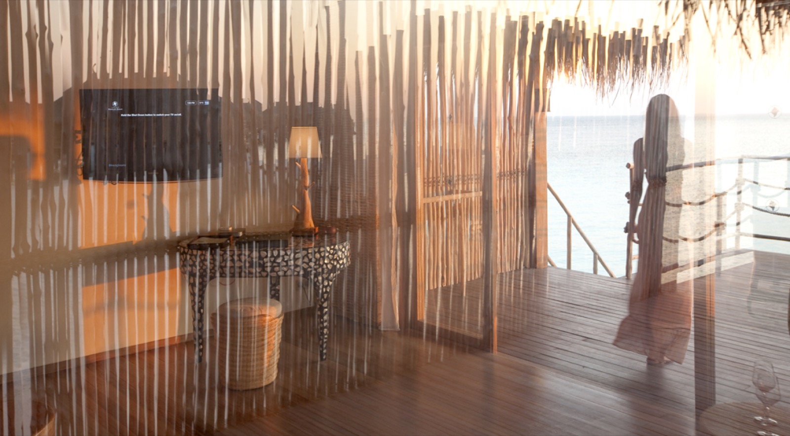 Bungalow sur l'eau à l'heure dorée du coucher de soleil, une femme en robe longue
