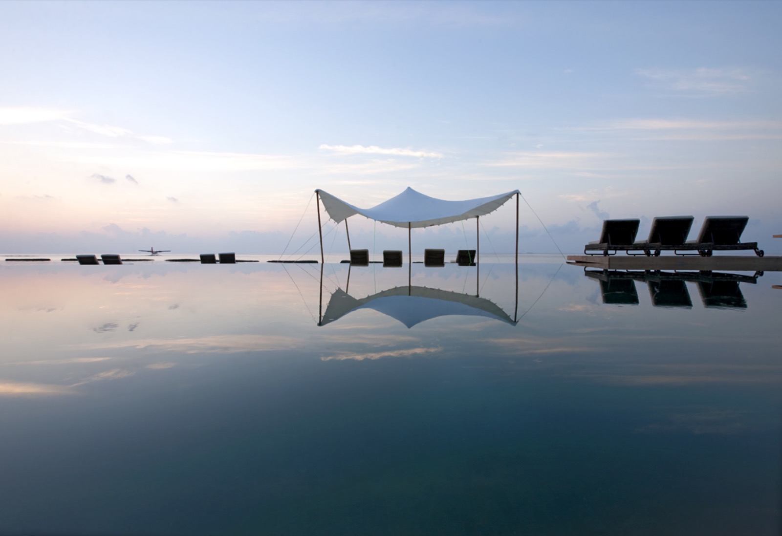 Piscine à débordement immobile reflétant un ciel pastel au crépuscule