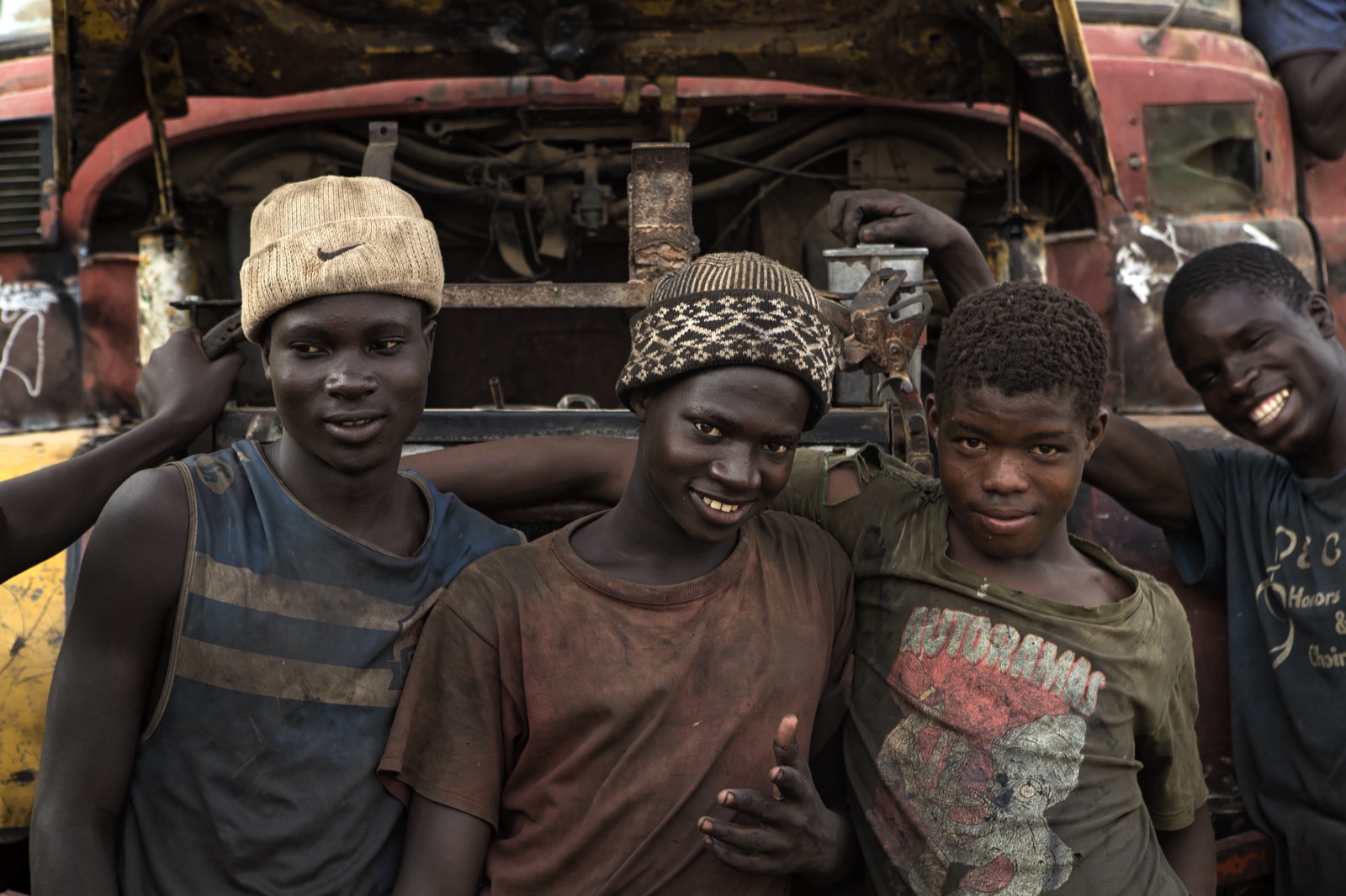 Quatre jeunes mécaniciens souriants devant le capot ouvert d'un camion
